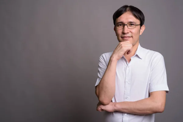 Young Asian nerd man wearing eyeglasses against gray background