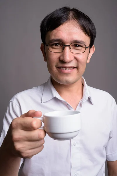 Young Asian nerd man wearing eyeglasses against gray background