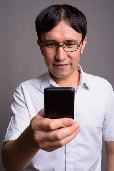 Ung asiatisk nörd man bär glasögon mot grå bakgrund — Stockfoto