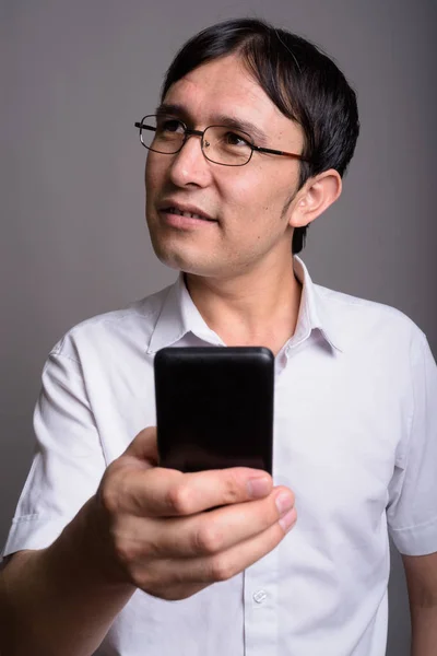 Young Asian nerd man wearing eyeglasses against gray background