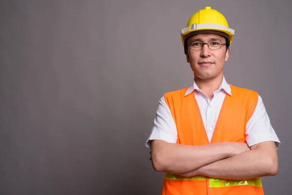 Młody człowiek Asian robotnik noszenie okularów przeciwko g — Zdjęcie stockowe