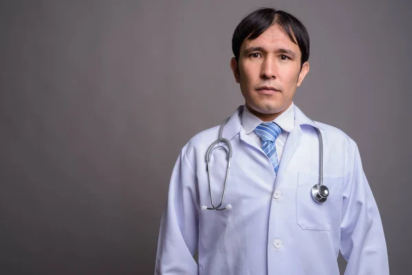 Joven asiático hombre médico contra gris fondo — Foto de Stock