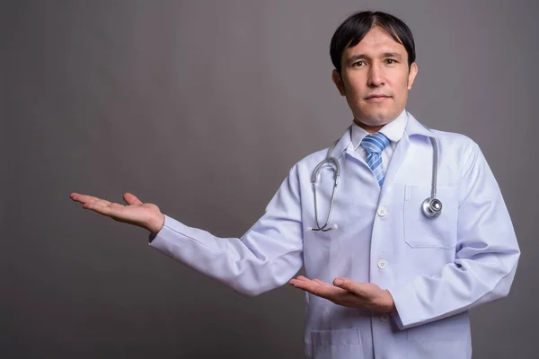 Joven asiático hombre médico contra gris fondo — Foto de Stock