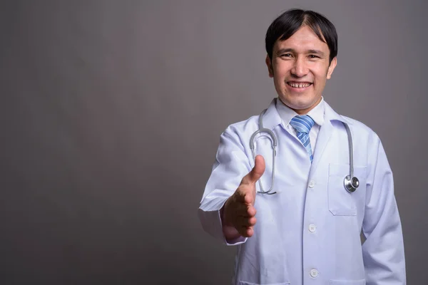 Молодой азиат врач на сером фоне — стоковое фото