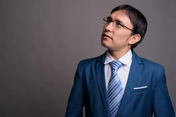 Portrait of young Asian businessman against gray background — Stock Photo, Image