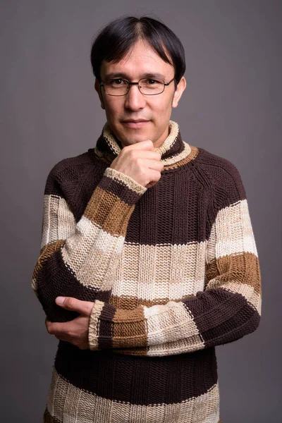Jovem ásia nerd homem vestindo gola alta suéter contra cinza bac — Fotografia de Stock