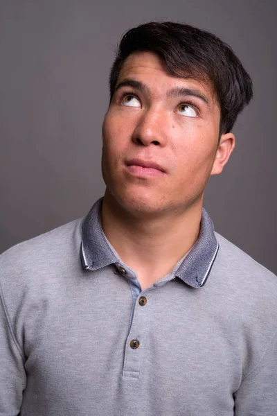Porträt eines jungen Asiaten vor grauem Hintergrund — Stockfoto