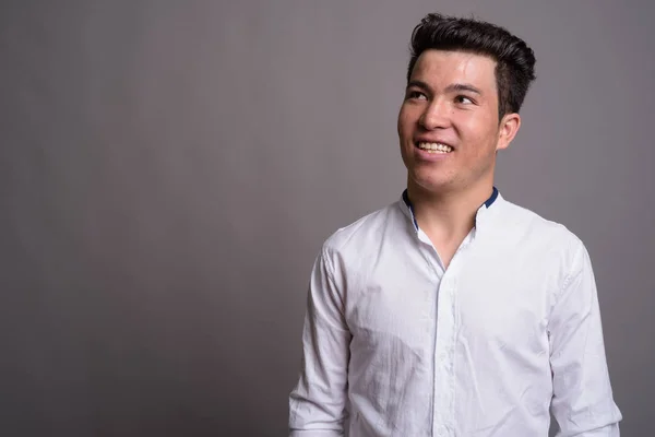 Retrato de jovem empresário asiático contra fundo cinza — Fotografia de Stock