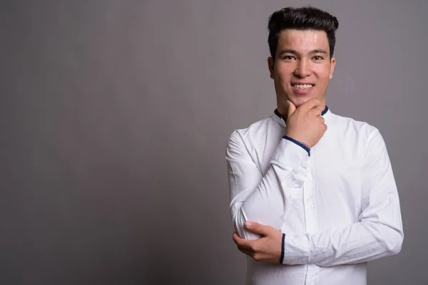 Portrét mladého asijského podnikatele na šedém pozadí — Stock fotografie