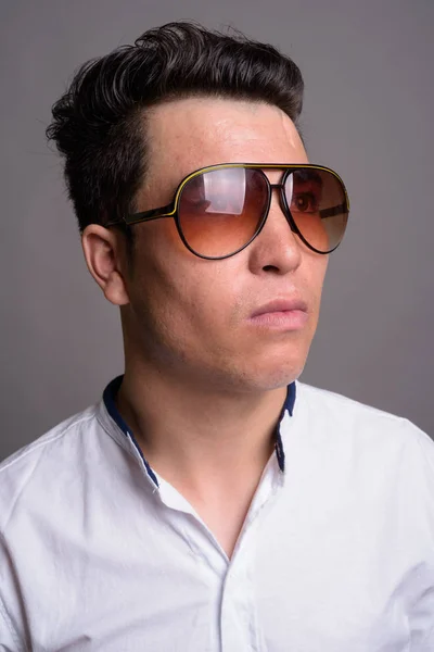 Giovane uomo d'affari asiatico indossa occhiali da sole contro backgrou grigio — Foto Stock