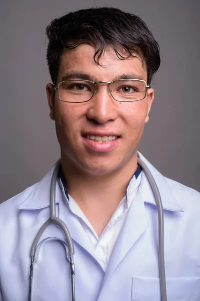Молодой азиат врач на сером фоне — стоковое фото