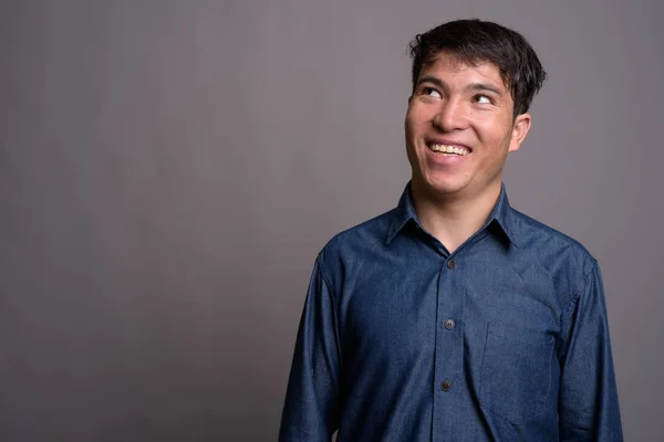 Joven asiático vistiendo camisa azul sobre fondo gris — Foto de Stock