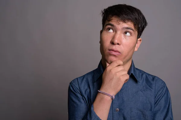 Junger Asiate trägt blaues Hemd vor grauem Hintergrund — Stockfoto