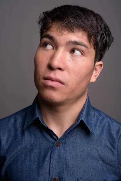 Giovane asiatico uomo indossare blu camicia contro grigio sfondo — Foto Stock