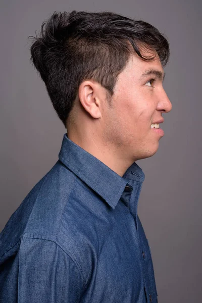 Joven asiático vistiendo camisa azul sobre fondo gris — Foto de Stock