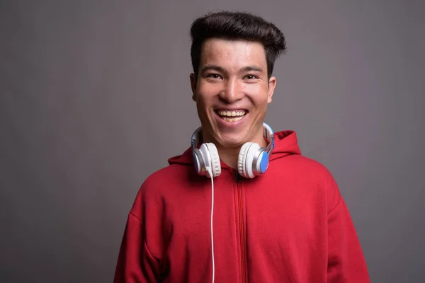 Junger Asiate trägt Kopfhörer vor grauem Hintergrund — Stockfoto