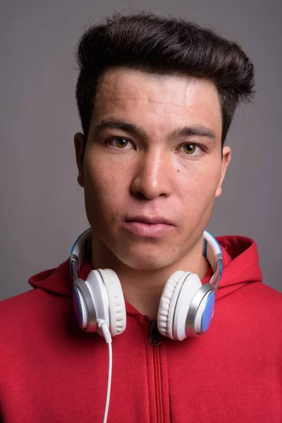 Junger Asiate trägt Kopfhörer vor grauem Hintergrund — Stockfoto