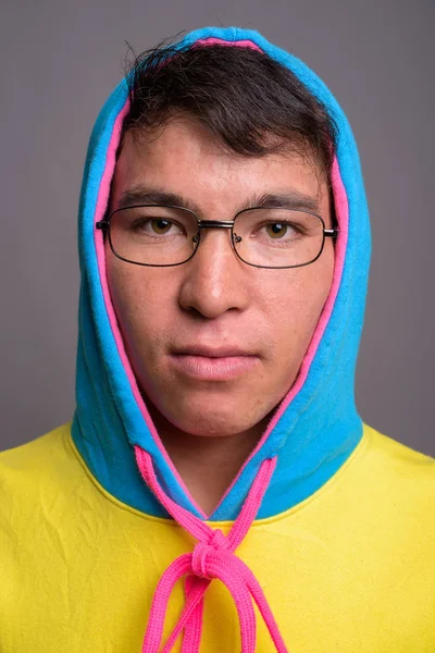 Joven asiático hombre usando sudadera con capucha de colores y gafas contra g — Foto de Stock