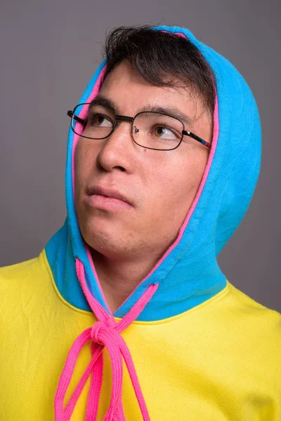 Joven asiático hombre usando sudadera con capucha de colores y gafas contra g — Foto de Stock