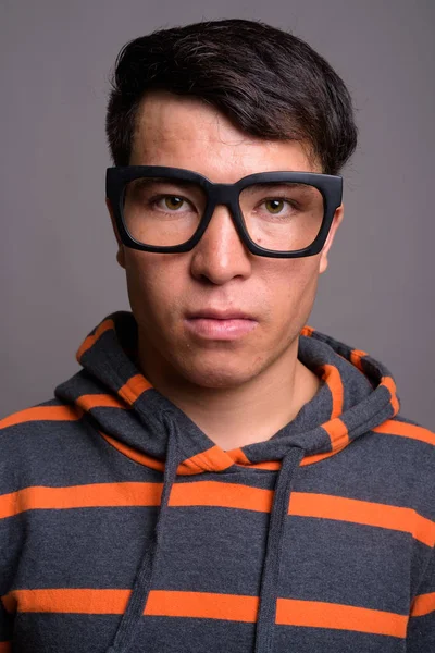 Jovem ásia nerd homem vestindo hoodie contra cinza fundo — Fotografia de Stock