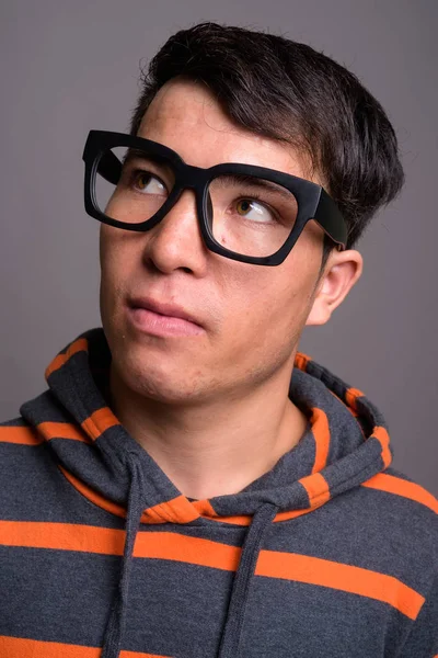 Giovane asiatico nerd uomo indossare felpa con cappuccio contro grigio sfondo — Foto Stock