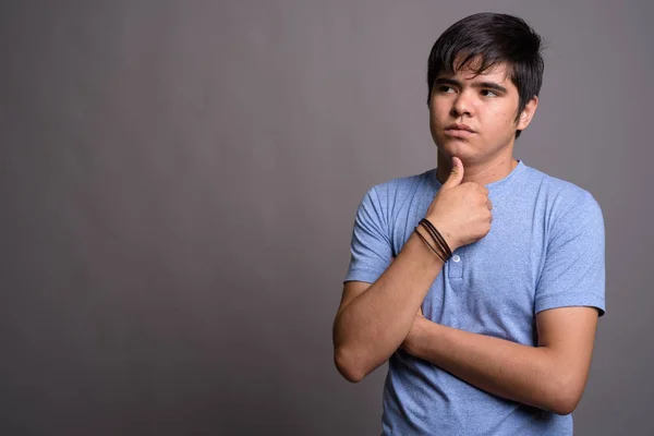 Junger asiatischer Teenager trägt blaues Hemd vor grauem Hintergrund — Stockfoto