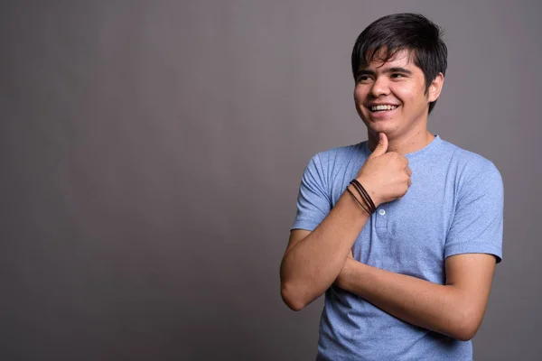 Joven adolescente asiático vistiendo camisa azul contra fondo gris —  Fotos de Stock