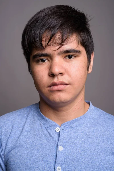 Joven adolescente asiático vistiendo camisa azul contra fondo gris — Foto de Stock