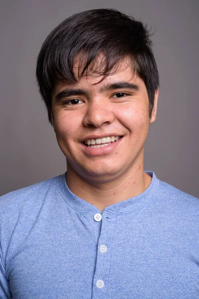 Joven adolescente asiático vistiendo camisa azul contra fondo gris — Foto de Stock