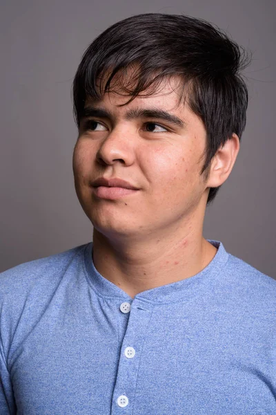 Joven adolescente asiático vistiendo camisa azul contra fondo gris — Foto de Stock