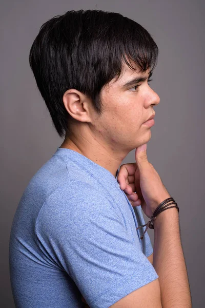 Fiatal ázsiai tizenéves fiú ellen szürke háttérb kék inget visel — Stock Fotó