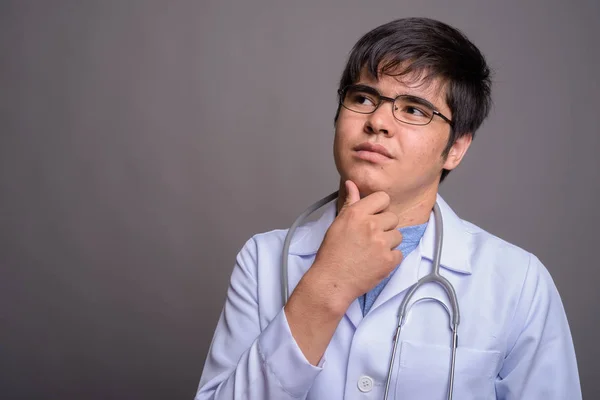 Młody Azji człowiek lekarz na szarym tle — Zdjęcie stockowe