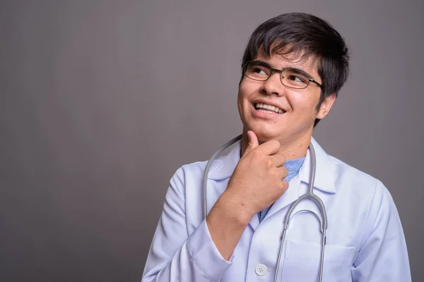 회색 배경에 반대하는 젊은 아시아인 의사 — 스톡 사진