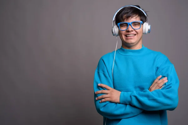 Młody chłopiec azjatyckich nastoletnich słuchanie muzyki przeciwko szary backgrou — Zdjęcie stockowe