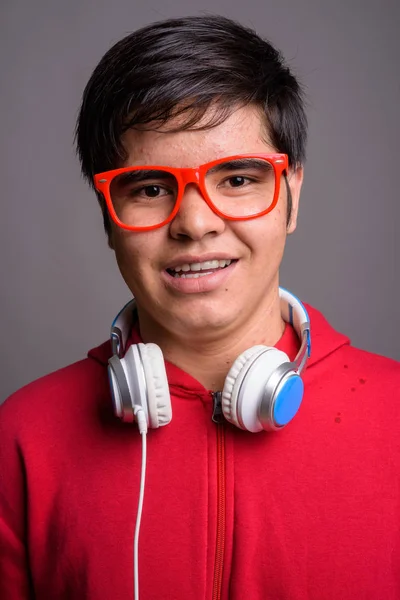 Jovem ásia adolescente menino vestindo fones de ouvido contra cinza backgrou — Fotografia de Stock