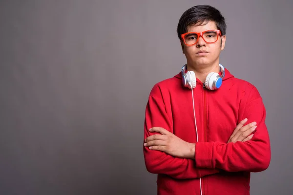 Młody chłopiec azjatyckich nastoletnich noszenia słuchawek przeciwko szary backgrou — Zdjęcie stockowe