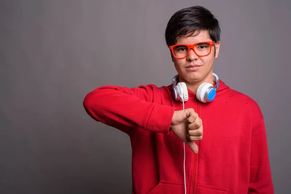 Jovem ásia adolescente menino vestindo fones de ouvido contra cinza backgrou — Fotografia de Stock