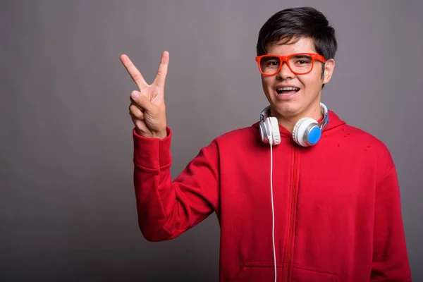 Joven adolescente asiático usando auriculares contra el backgrou gris — Foto de Stock