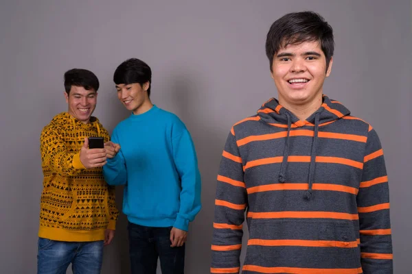 Drei junge asiatische Freunde vor grauem Hintergrund — Stockfoto