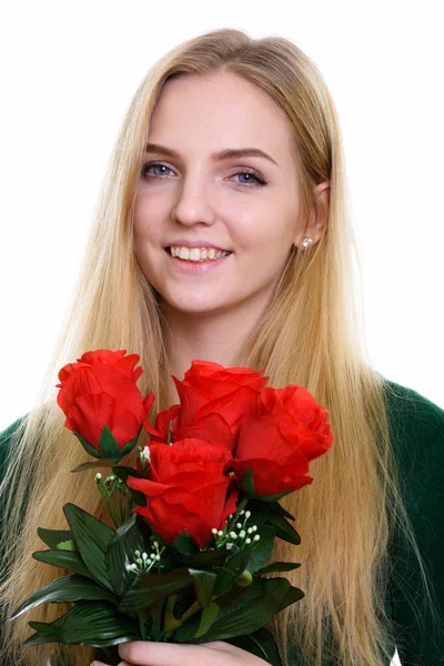 对年轻快乐的少女，微笑着拿着红玫瑰的脸上 — 图库照片