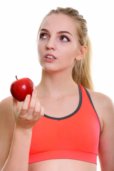 Face of young beautiful teenage girl holding red apple while thi — Stock Photo, Image