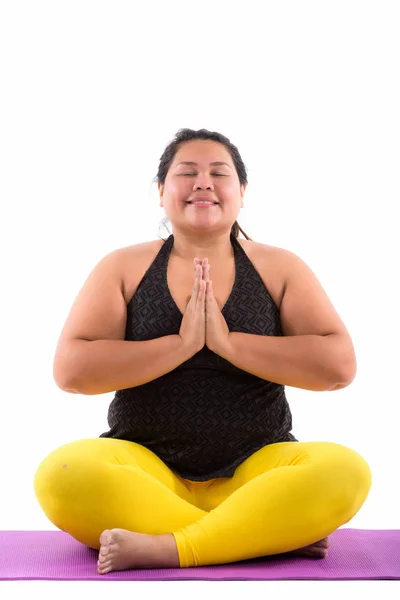 Estudio disparo de joven feliz grasa asiática mujer sonriendo mientras meditat —  Fotos de Stock