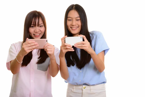 Two young happy Asian teenage girls smiling and taking picture w — Stock Photo, Image