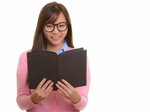 Young happy Asian teenage girl smiling and reading book Royalty Free Stock Photos