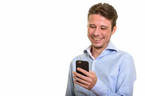 Счастливый кавказский бизнесмен улыбается и пользуется мобильным телефоном — стоковое фото