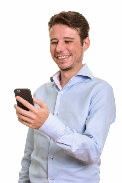 Счастливый кавказский бизнесмен улыбается и держит в руках мобильный телефон — стоковое фото