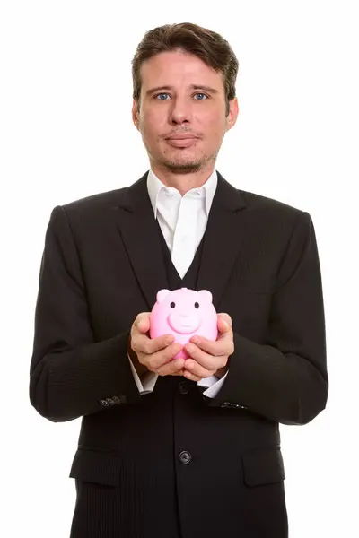 Kaukasischer Geschäftsmann hält Sparschwein und schaut in die Kamera — Stockfoto