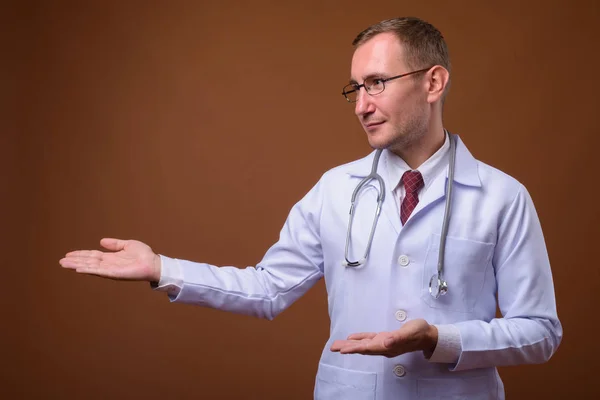 Студійний знімок лікаря чоловіка на коричневому фоні — стокове фото