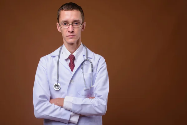 Studio colpo di giovane medico contro sfondo marrone — Foto Stock