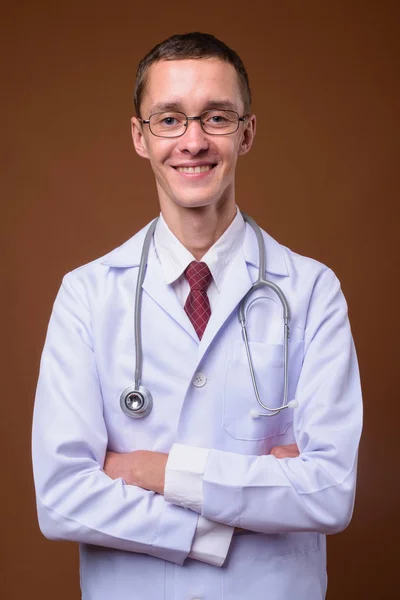 Estúdio tiro de jovem médico contra fundo marrom — Fotografia de Stock